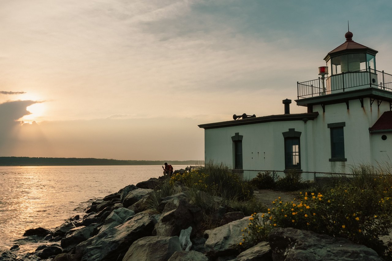 A serene view of a lighthouse by the water during sunset in Seattle, WA, USA.