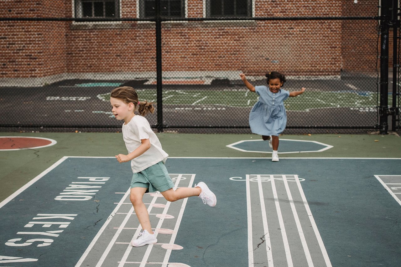Two young girls playing hopscotch in a playground, filled with joy and movement.