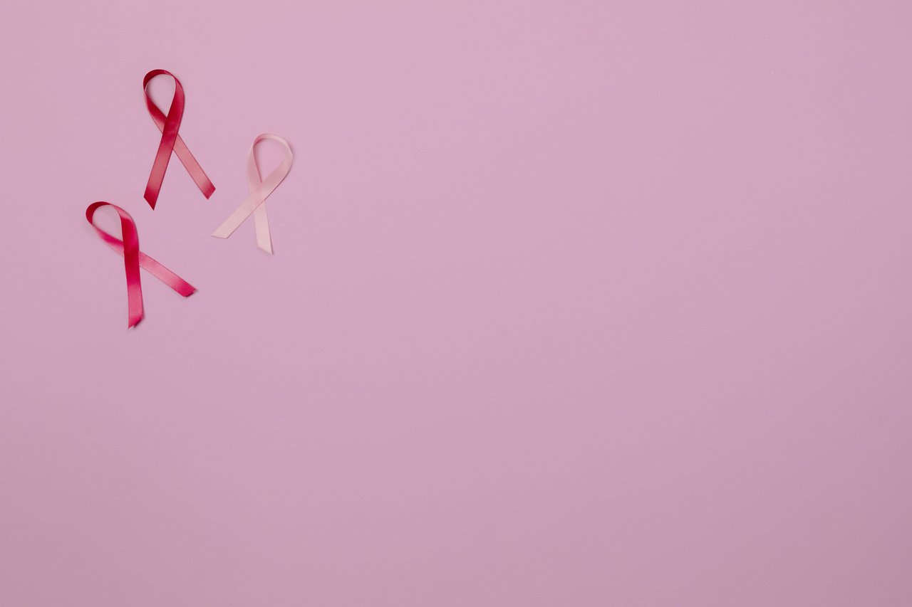 Three pink ribbons on a pink background symbolizing breast cancer awareness.