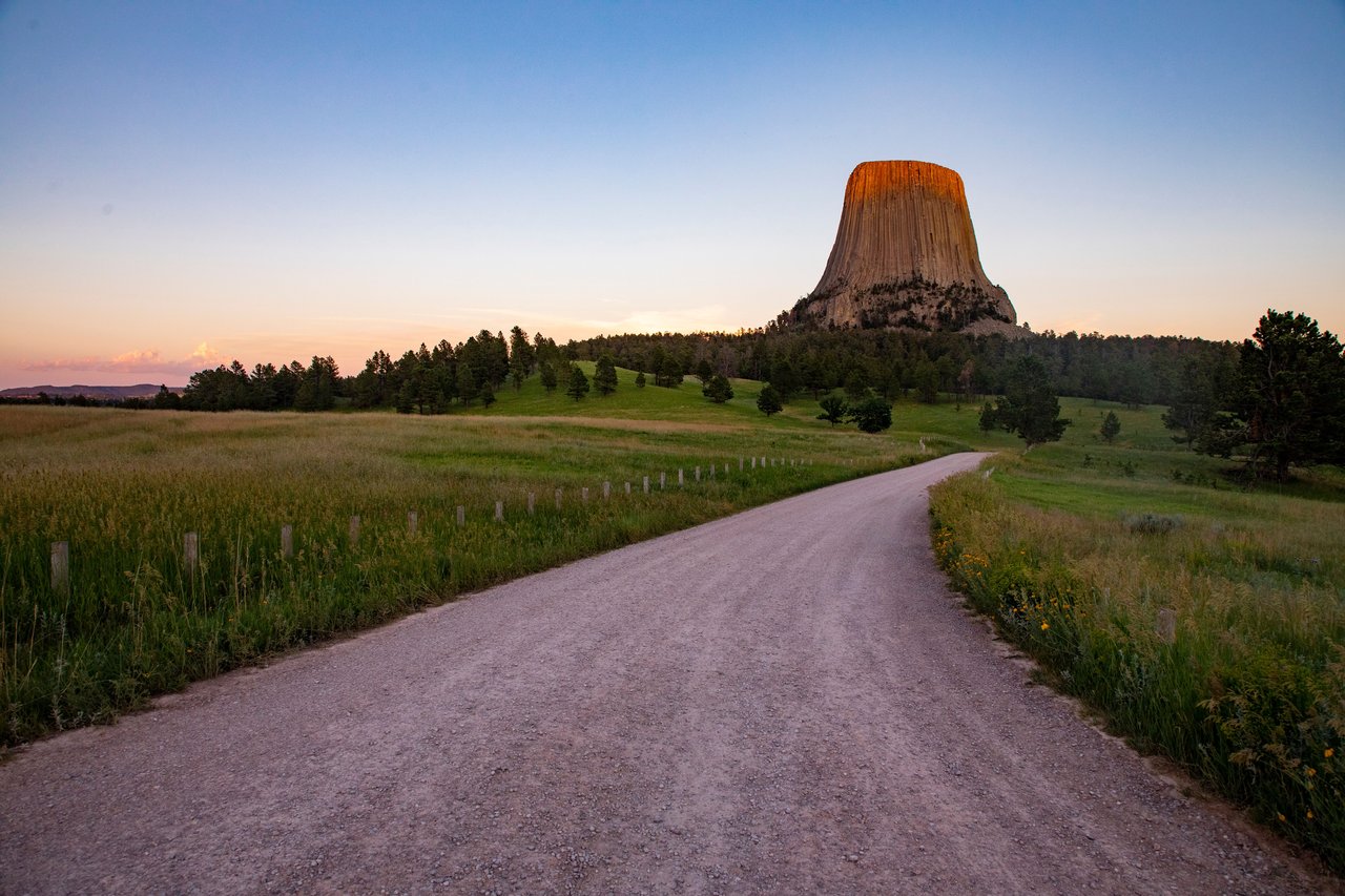 Beautiful sunset at Devils Tower, Wyoming with a winding road leading to the monument.