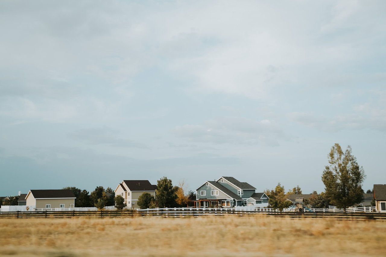 Scenic view of countryside homes with a wooden fence under a wide sky near Denver, Colorado.