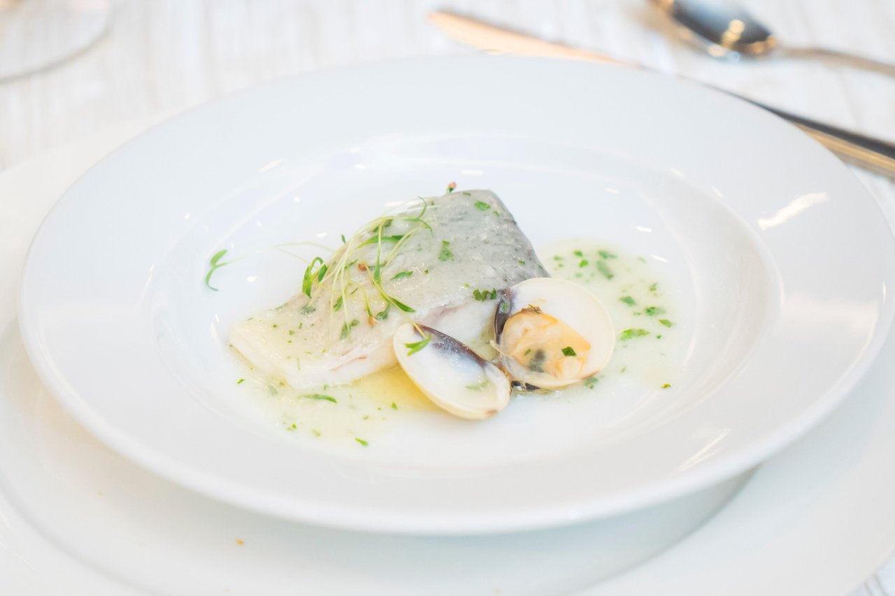 Artistic presentation of seafood with clams and herbs on a white plate.