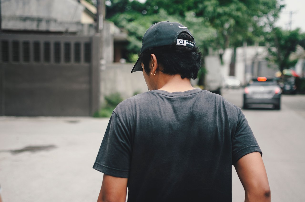 Back view of a man walking casually down a street in a tropical urban environment, Cebu City.