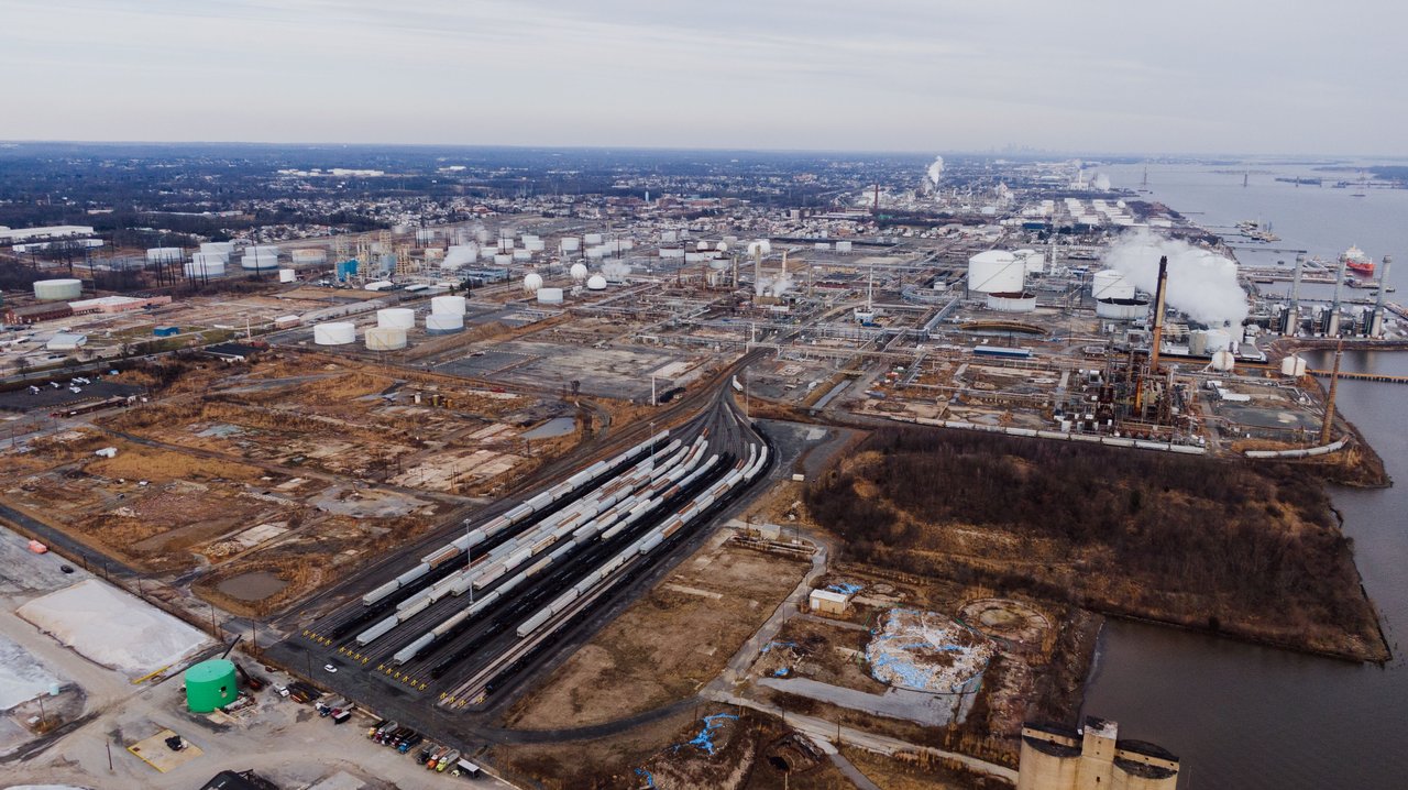 Drone view of industrial district of town surrounded with water of river under cloudy sky
