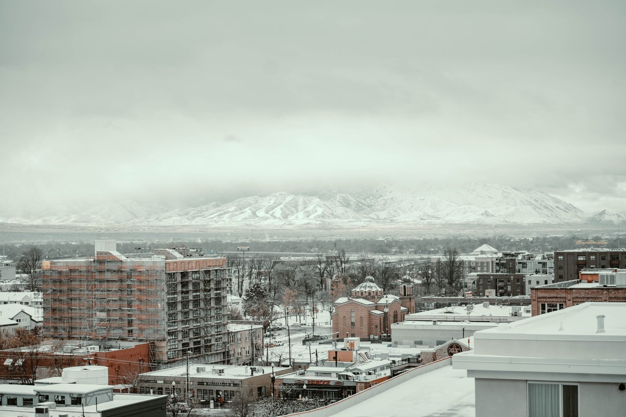 A winter cityscape view in Salt Lake City with snow-covered buildings and mountains in the background.