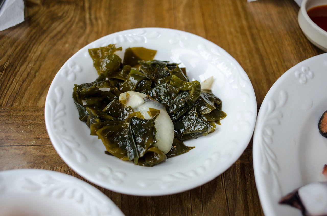 Close-up of a fresh seaweed and onion salad served on a white plate.
