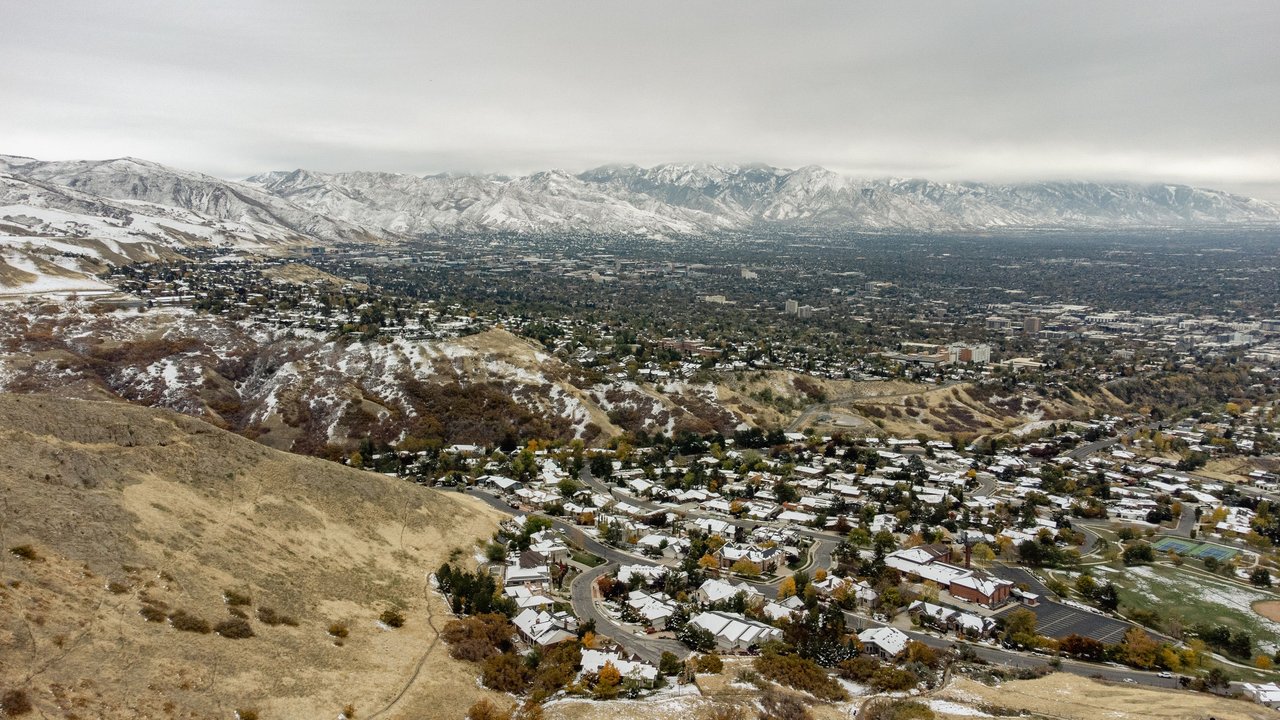 A stunning aerial perspective of snow-dusted Salt Lake City, highlighting its winter landscape and surrounding mountains.