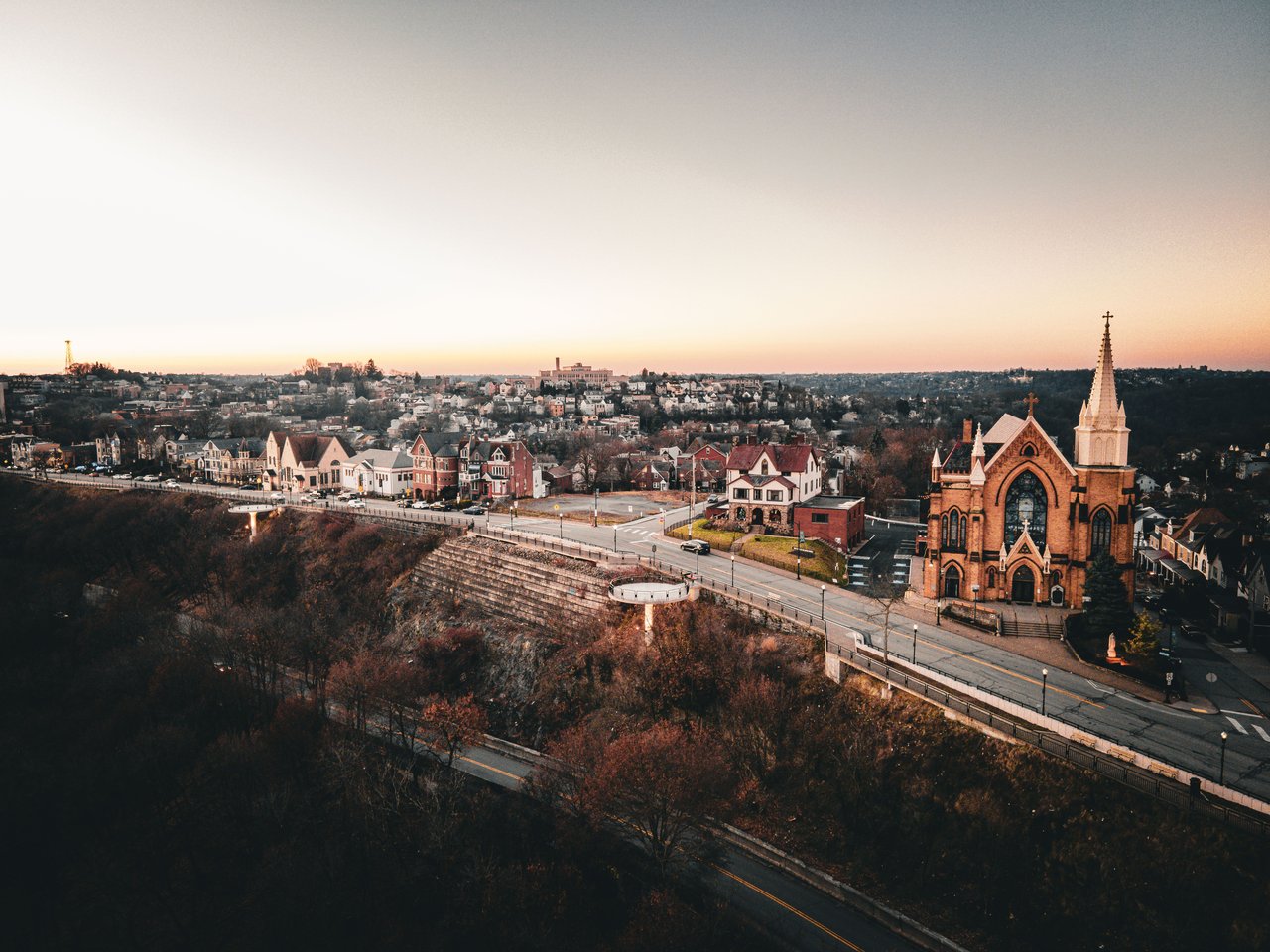 Stunning aerial view of Pittsburgh at sunset, showcasing a historic church and charming neighborhood.