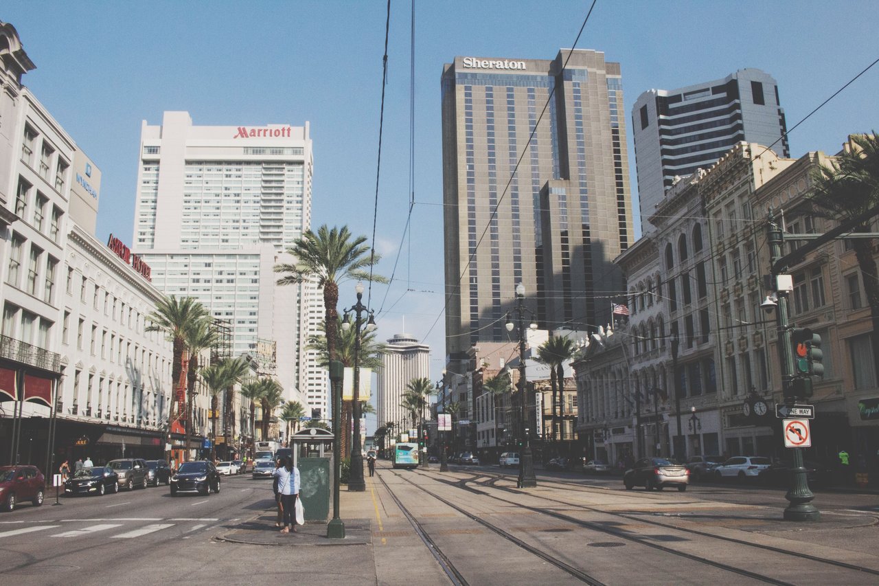 Bustling street view of downtown New Orleans, showcasing high-rise buildings and city life.