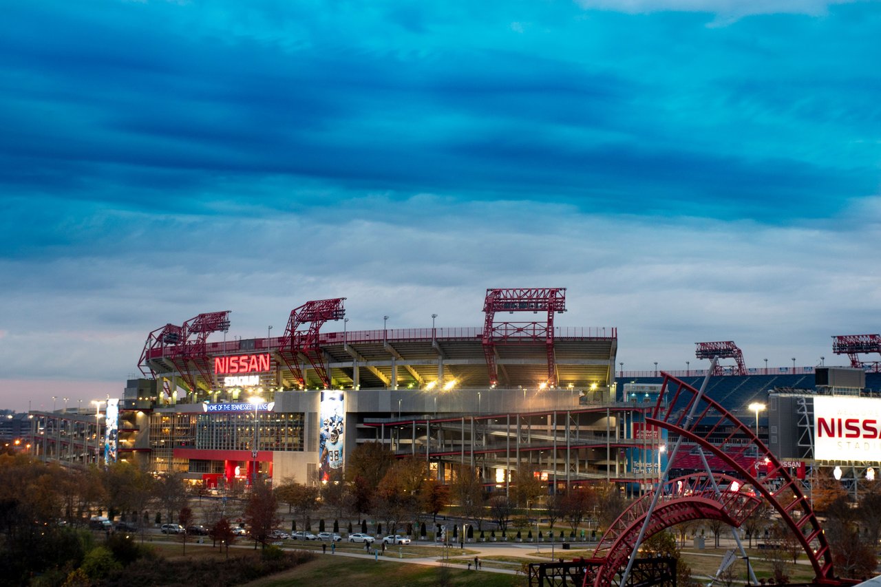 View of Nissan Stadium in Nashville, Tennessee, under a dramatic cloudy sky at dusk.