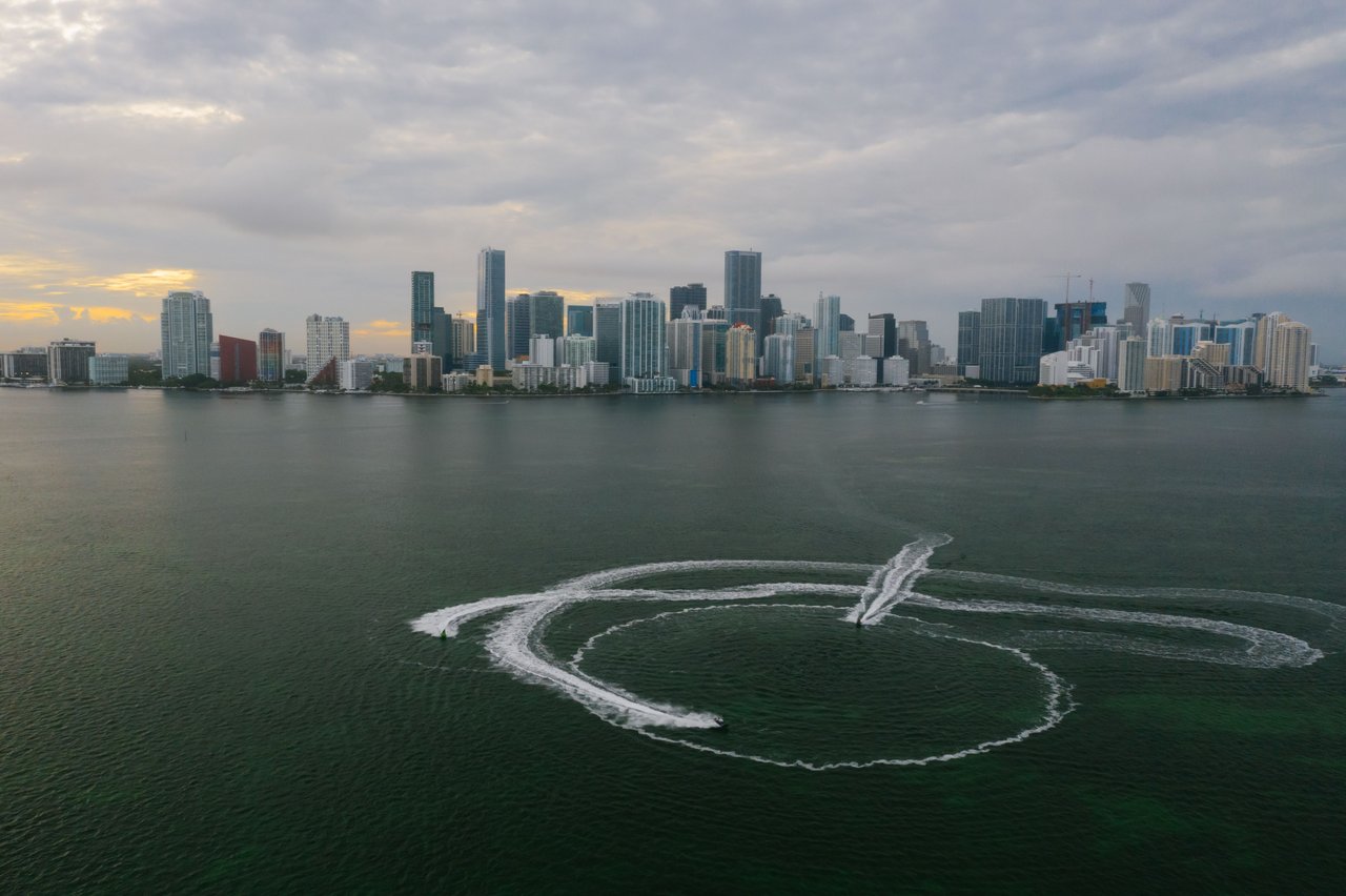 Aerial shot of Miami's skyline with watercraft patterns on the ocean surface.