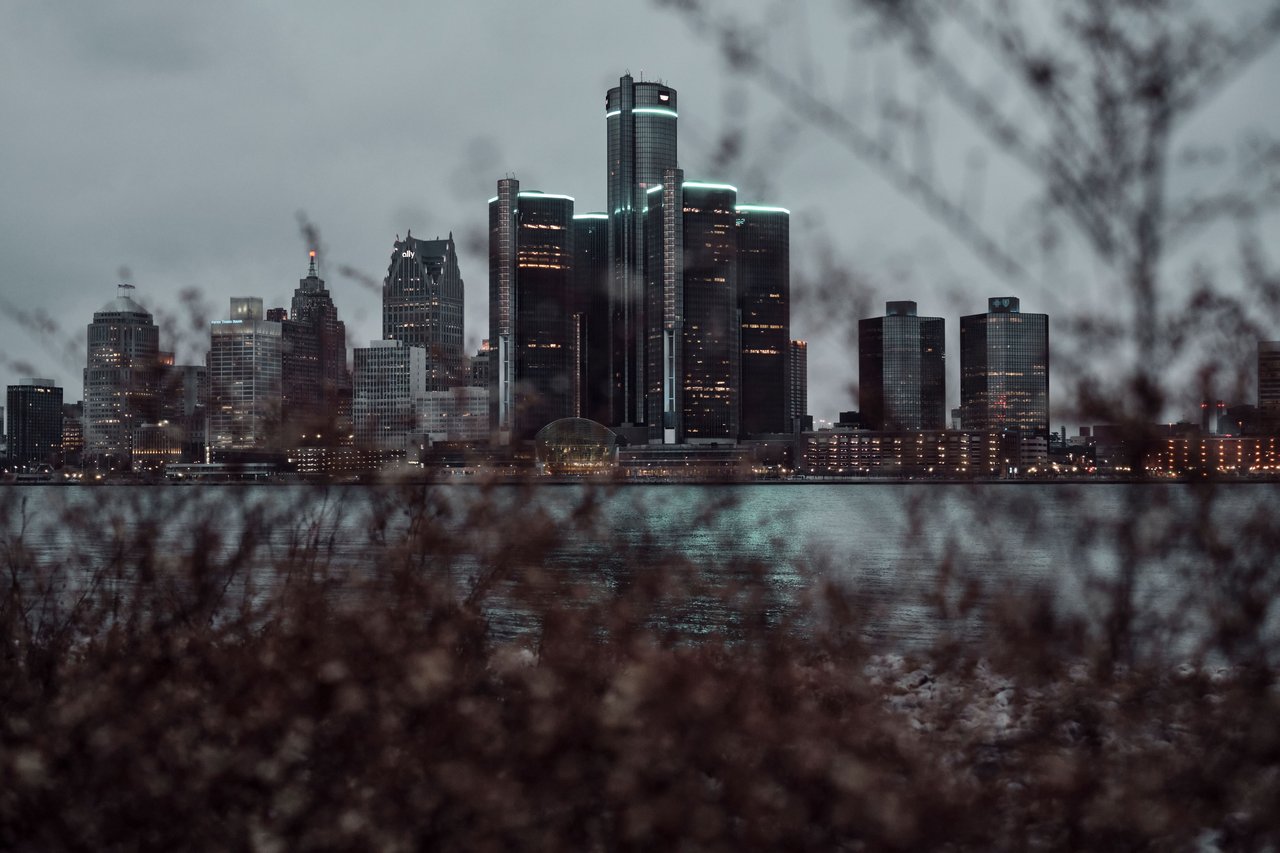 Dramatic view of the Detroit skyline across the waterfront at dusk, featuring skyscrapers.