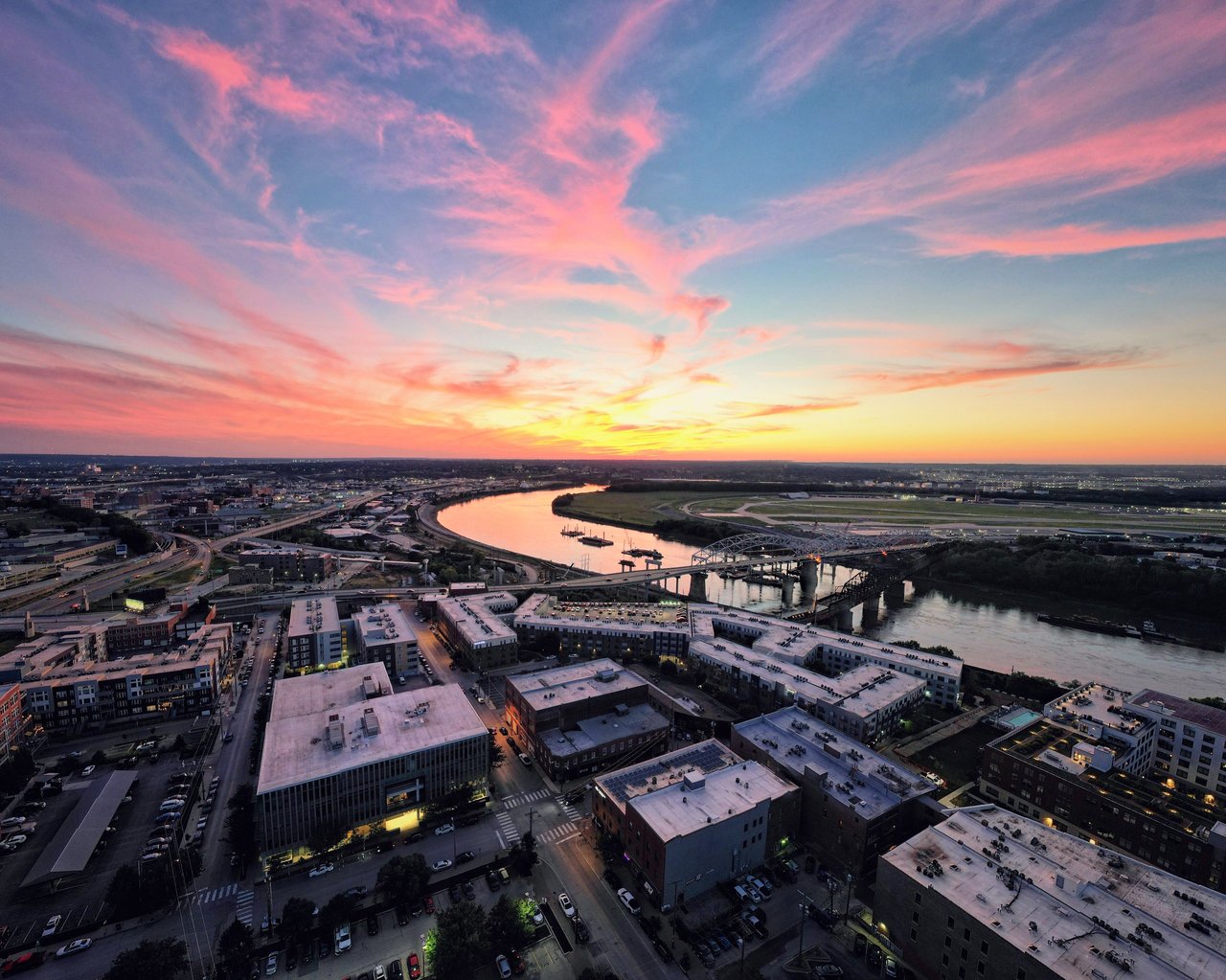 A vibrant sunset over Kansas City's urban landscape and river, highlighting the city's architecture and colorful sky.