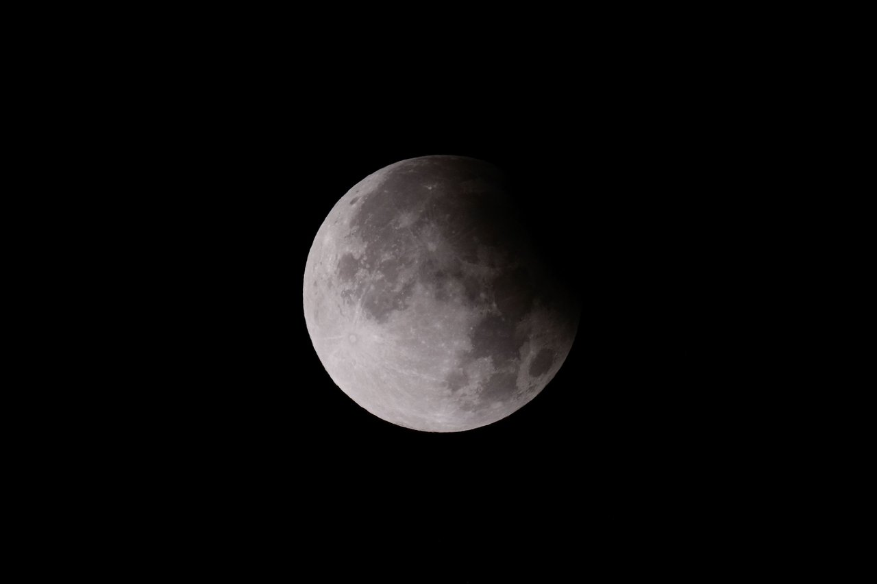 Close-up shot of a lunar eclipse, showcasing the moon's surface with shadow play.