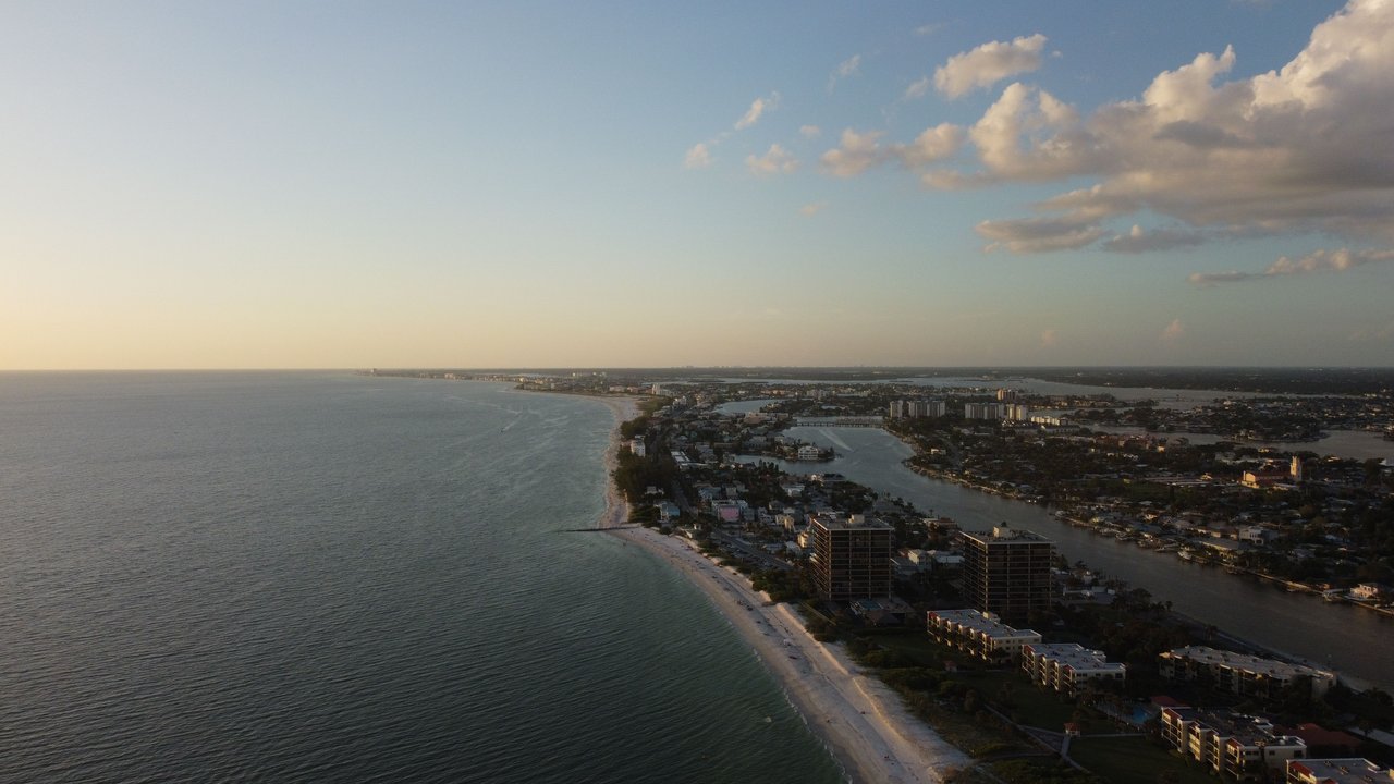 Dramatic aerial view of a coastal city with stunning sunset lighting and expansive ocean vistas.