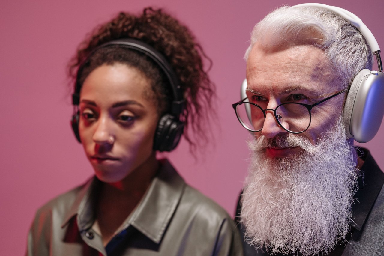 A young woman and an elderly man with headphones, deeply engaged in listening.