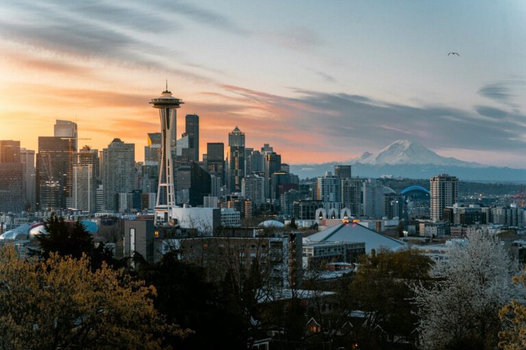 The Space Needle and Seattle skyline with Mount Rainier under a warm orange sky